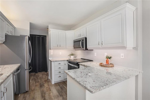 kitchen featuring tasteful backsplash, white cabinets, dark wood-style flooring, a peninsula, and stainless steel appliances