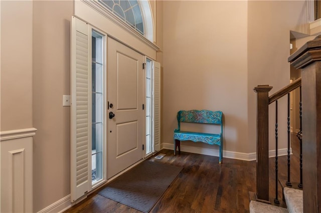 foyer entrance with dark wood finished floors, a high ceiling, stairway, and baseboards