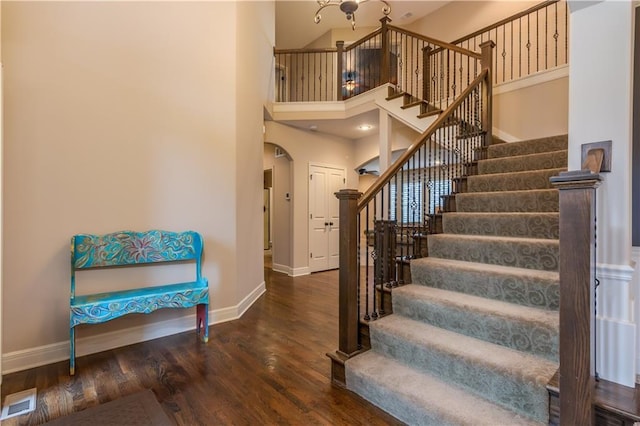 stairs featuring visible vents, wood finished floors, arched walkways, and baseboards