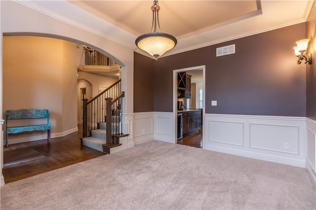 empty room featuring visible vents, stairway, carpet flooring, arched walkways, and a raised ceiling