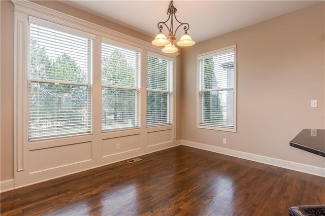 unfurnished dining area featuring visible vents, baseboards, dark wood-style flooring, and a chandelier