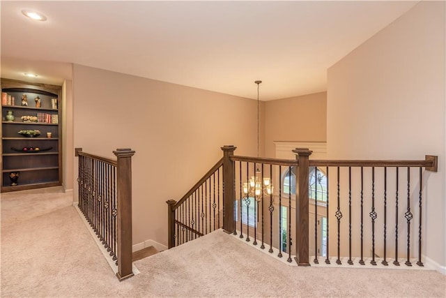 staircase with baseboards, a notable chandelier, and carpet flooring