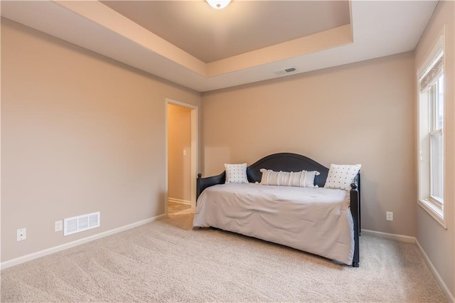 carpeted bedroom featuring visible vents, baseboards, and a tray ceiling