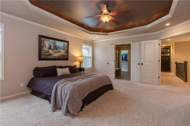 carpeted bedroom with a ceiling fan, a raised ceiling, baseboards, and ornamental molding