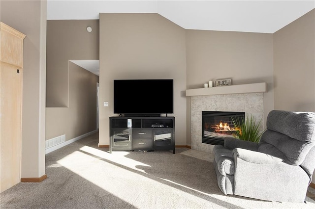 living area with visible vents, baseboards, carpet, a tiled fireplace, and vaulted ceiling