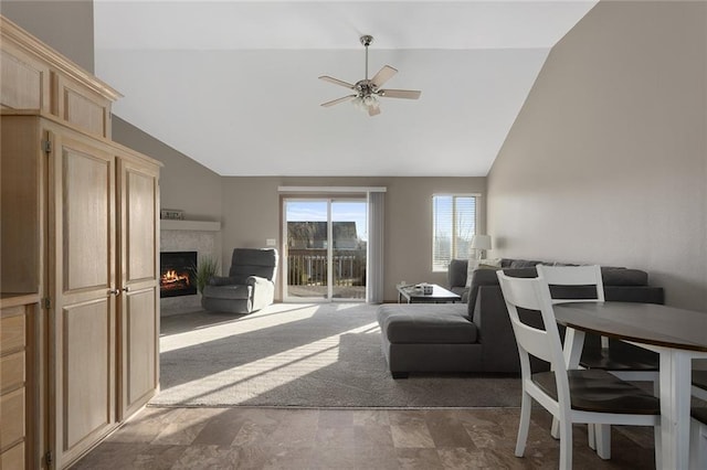 living area featuring a warm lit fireplace, high vaulted ceiling, and a ceiling fan