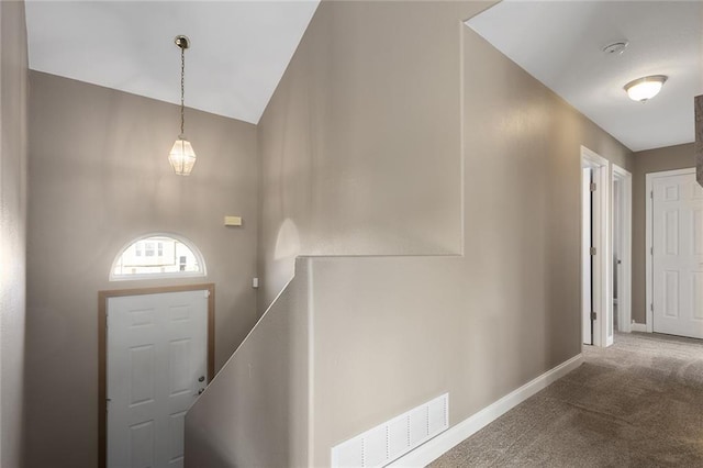 carpeted foyer featuring visible vents, baseboards, and lofted ceiling