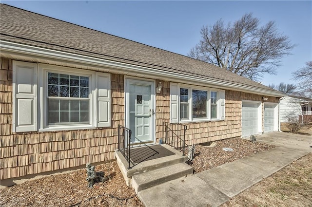 view of front of house featuring a garage, concrete driveway, and roof with shingles