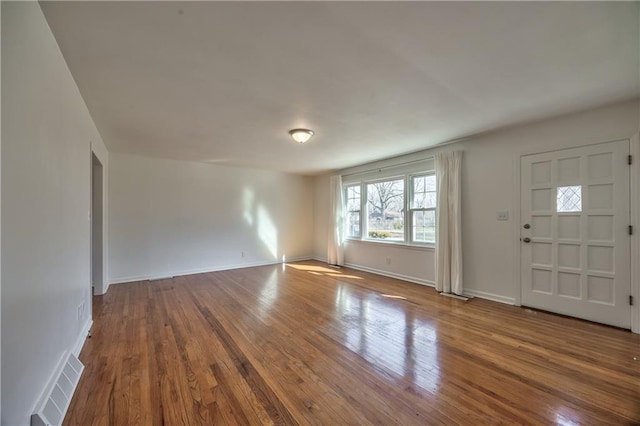 foyer with baseboards, visible vents, and hardwood / wood-style floors