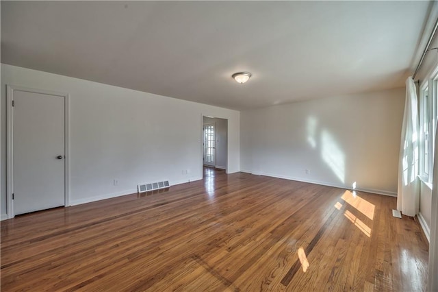 empty room featuring visible vents, baseboards, and wood finished floors