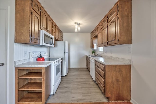 kitchen with white appliances, baseboards, light countertops, open shelves, and light wood finished floors