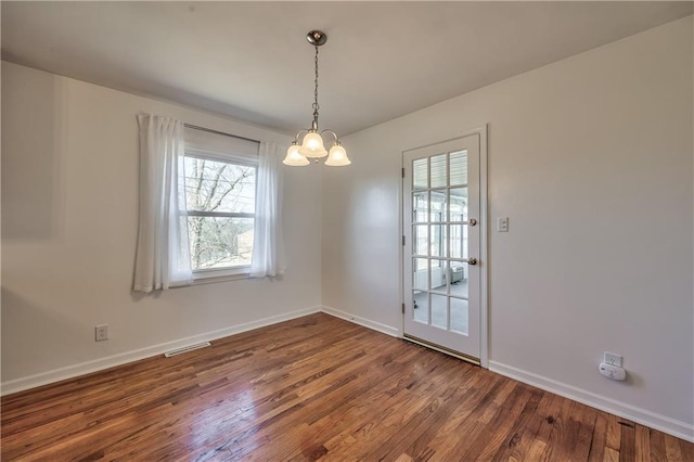 unfurnished dining area with a chandelier, visible vents, baseboards, and wood finished floors