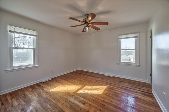 unfurnished room featuring wood-type flooring, visible vents, baseboards, and ceiling fan