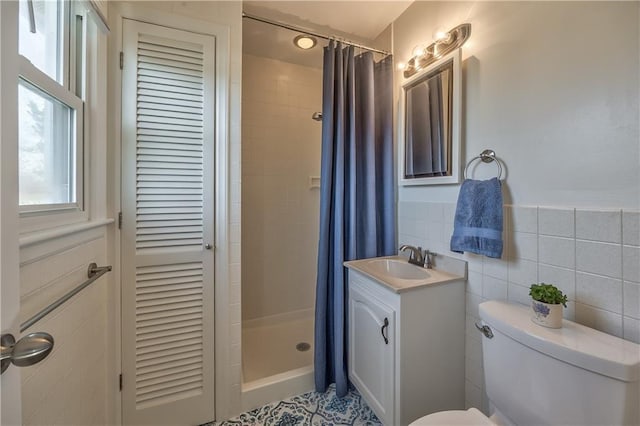 full bath featuring tile walls, toilet, vanity, a shower stall, and a closet