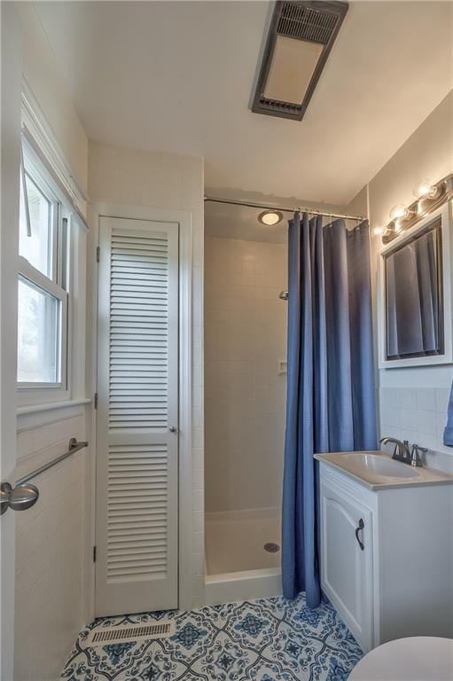 bathroom with tile patterned floors, vanity, visible vents, decorative backsplash, and a stall shower