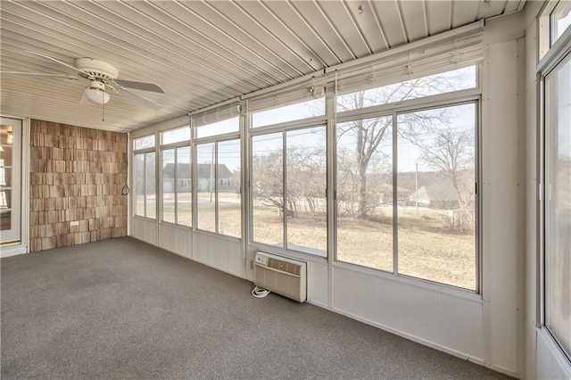 unfurnished sunroom with wooden ceiling, a wall unit AC, a wealth of natural light, and a ceiling fan