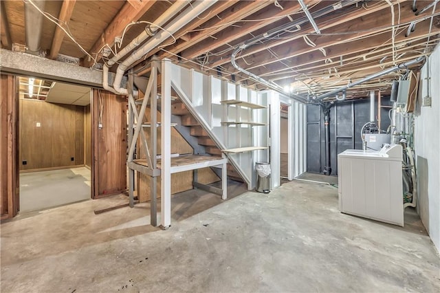 unfinished below grade area with stairs, washer / clothes dryer, and wooden walls