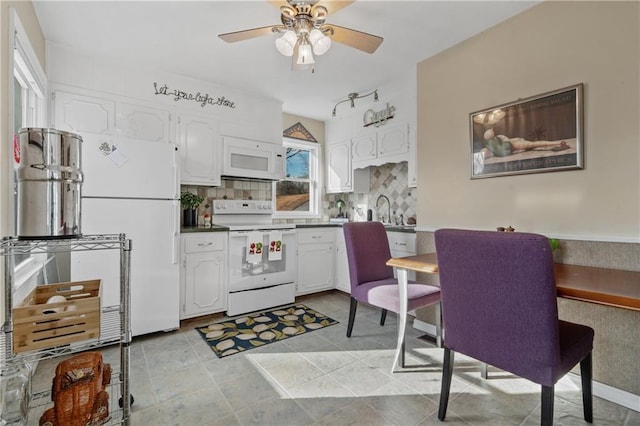 kitchen with white appliances, a ceiling fan, a sink, decorative backsplash, and white cabinetry