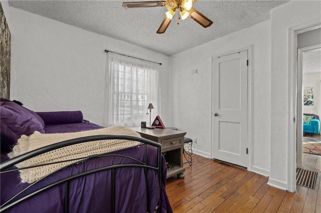 bedroom with baseboards, a textured ceiling, a textured wall, and hardwood / wood-style flooring