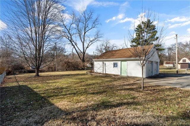 view of yard with an outbuilding, a detached garage, and fence