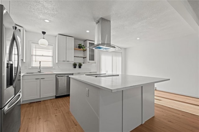 kitchen with island exhaust hood, stainless steel appliances, light wood-style floors, and a sink