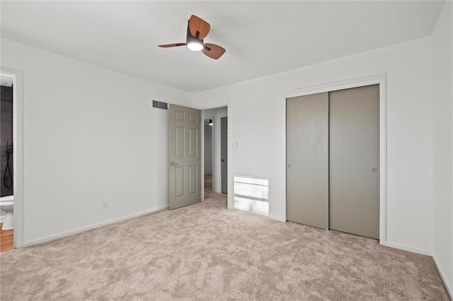 unfurnished bedroom featuring a ceiling fan, visible vents, a closet, carpet flooring, and connected bathroom