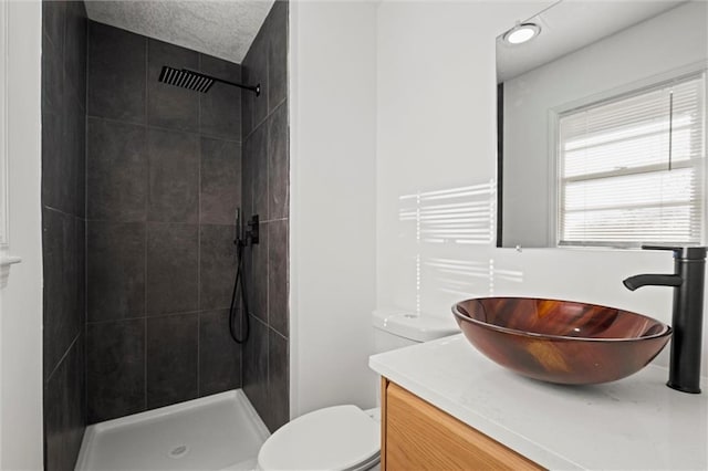 bathroom featuring tiled shower, toilet, and vanity