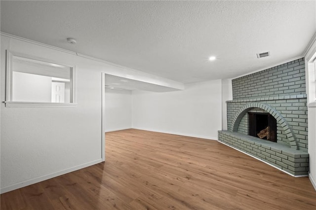 unfurnished living room with wood finished floors, a fireplace, visible vents, and a textured ceiling