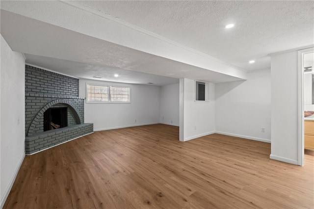 below grade area featuring a textured ceiling, a brick fireplace, and wood finished floors