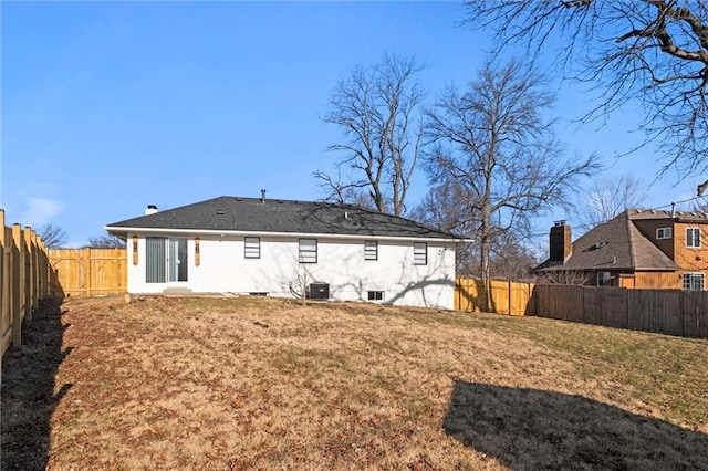 rear view of property with cooling unit, a lawn, and a fenced backyard