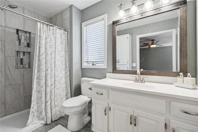 bathroom featuring vanity, toilet, ceiling fan, and tiled shower