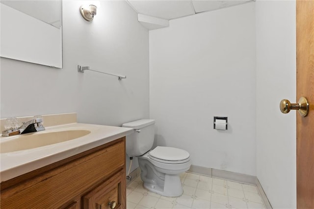 half bathroom with tile patterned floors, baseboards, toilet, and vanity