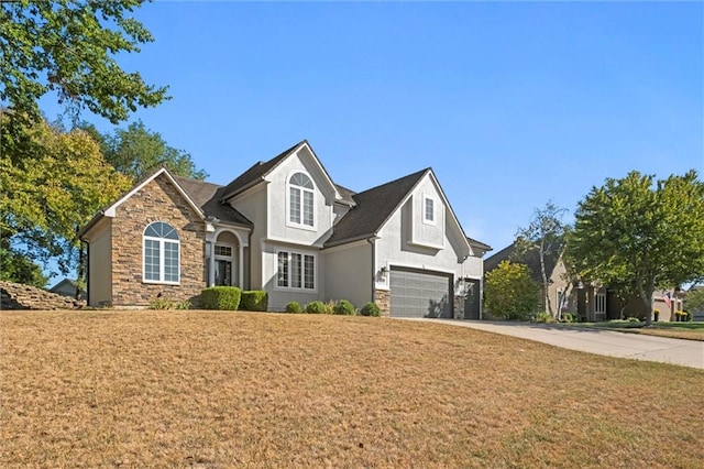 traditional-style home featuring stucco siding, a garage, stone siding, driveway, and a front lawn