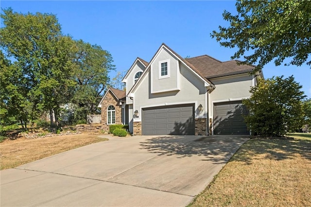 view of front facade with an attached garage, driveway, stone siding, stucco siding, and a front yard