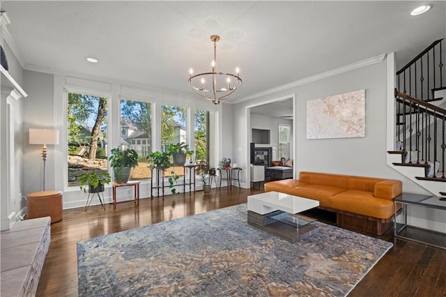 living room featuring crown molding, stairs, wood finished floors, and a glass covered fireplace