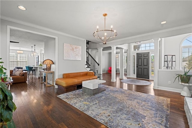 living room featuring wood finished floors, stairway, ornate columns, and an inviting chandelier