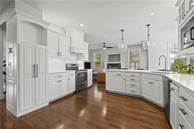 kitchen with stainless steel appliances, a peninsula, a sink, open floor plan, and custom range hood