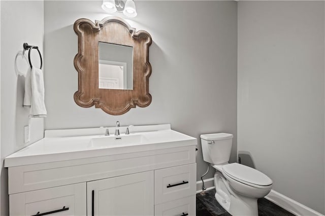 bathroom featuring toilet, baseboards, and vanity