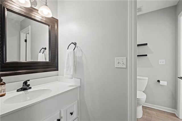 bathroom featuring baseboards, vanity, toilet, and wood finished floors