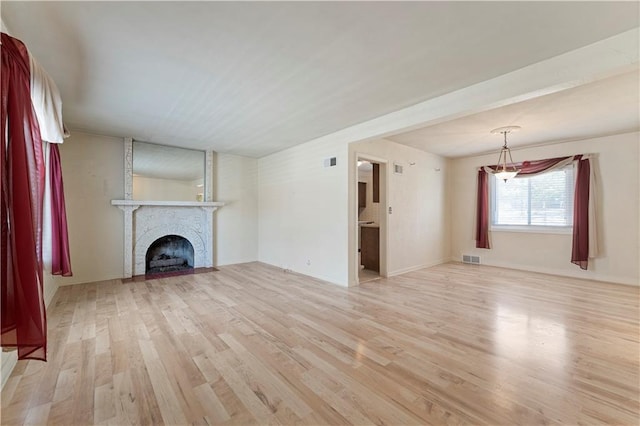 unfurnished living room featuring light wood-style flooring, a fireplace, and visible vents