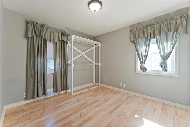 spare room with baseboards, a wealth of natural light, and wood finished floors