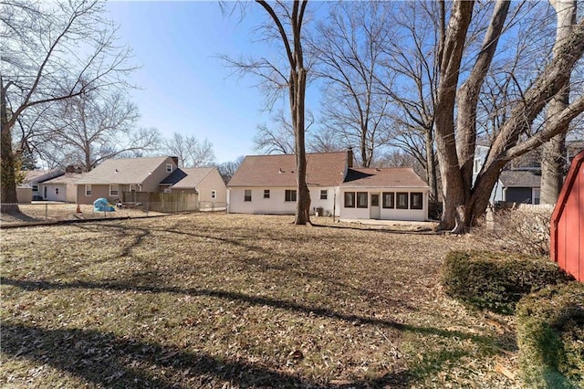 rear view of property with a lawn, fence, and a sunroom