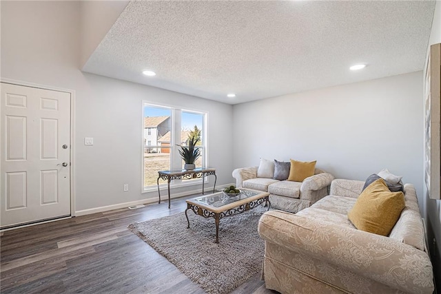 living area featuring baseboards, dark wood finished floors, a textured ceiling, and recessed lighting