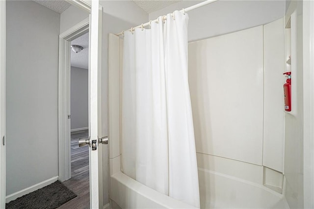 full bathroom featuring a textured ceiling, wood finished floors, and baseboards