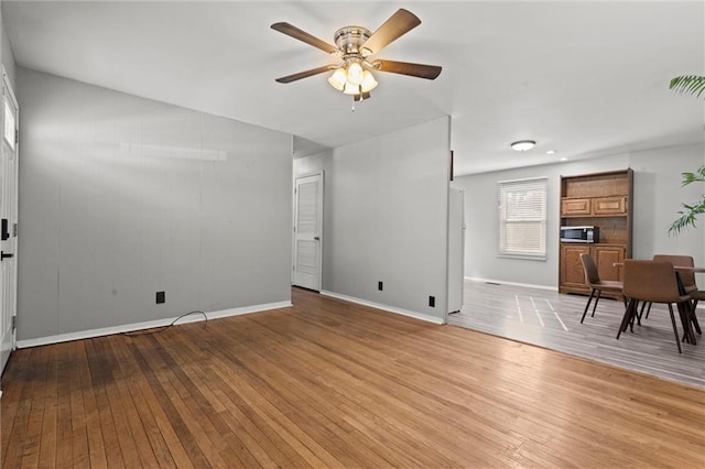 unfurnished living room featuring light wood-type flooring, ceiling fan, and baseboards