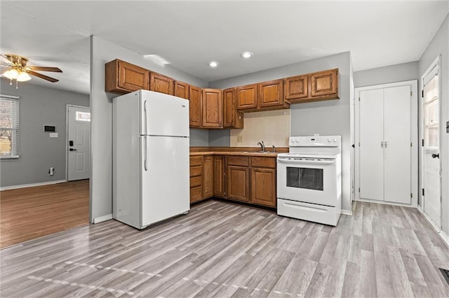 kitchen featuring white appliances, plenty of natural light, light wood-style flooring, and brown cabinets