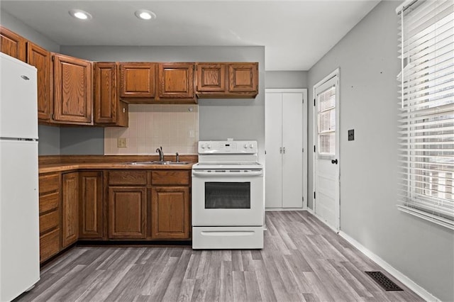 kitchen featuring visible vents, white appliances, a sink, and a wealth of natural light