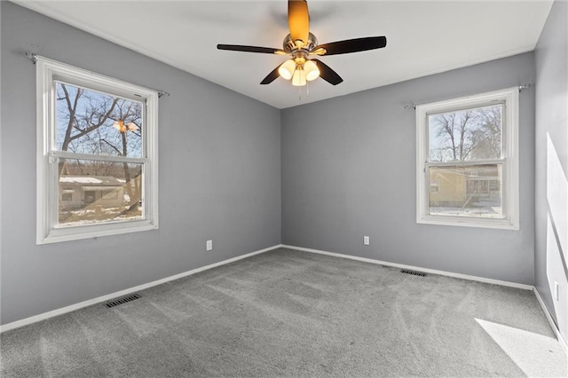 unfurnished room with carpet floors, baseboards, visible vents, and ceiling fan