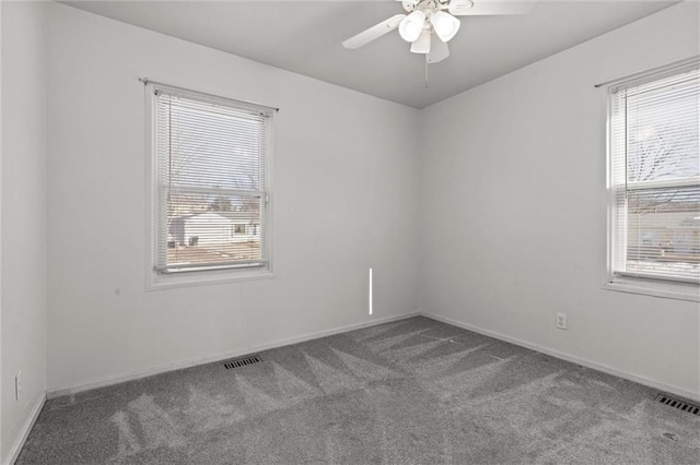 carpeted spare room with ceiling fan, plenty of natural light, and visible vents