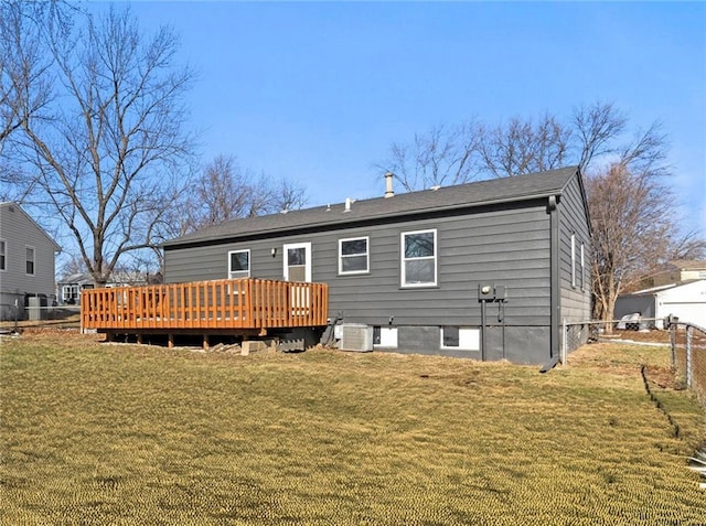 back of property with a lawn, a deck, central AC unit, and fence